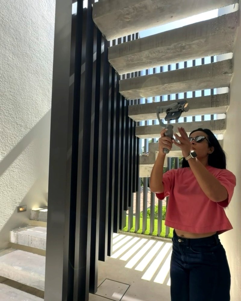 Sonia Cot grabando con estabilizador en una casa de Miami, junto a la celosía metálica